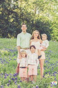 happy family with three kids standing in bluebonnets