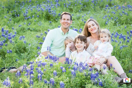 happy family with three kids sitting in bluebonnets