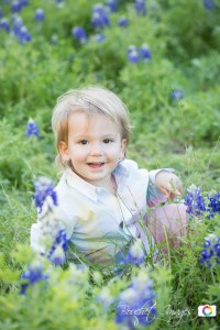 little kid smiling sitting in bluebonnets