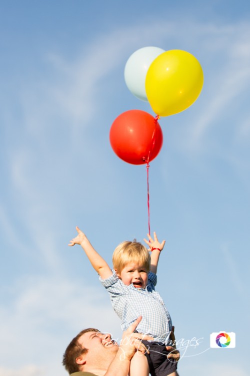 little kid holding colorful helium balloons like Curious George
